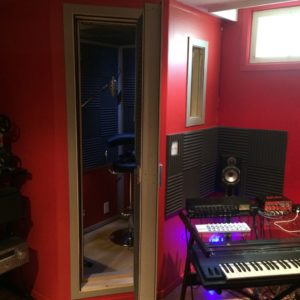 Exterior view of vocal isocaltion recording booth in corner of studio.